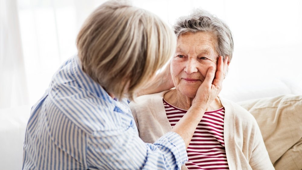 Tochter im Gespräch mit ihrer älteren Mutter im Wohnzimmer