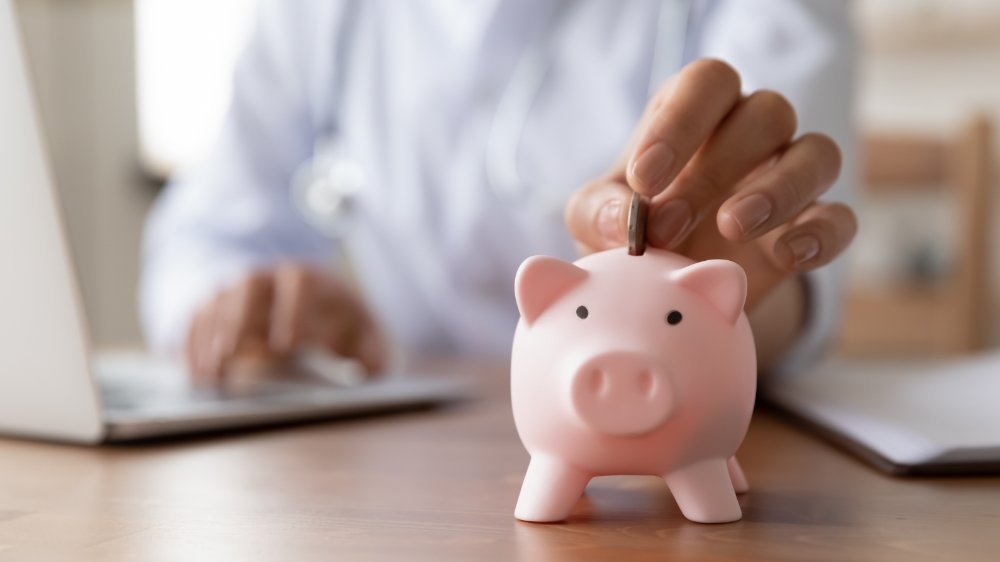 Arzt steckt Geld ins Sparschwein